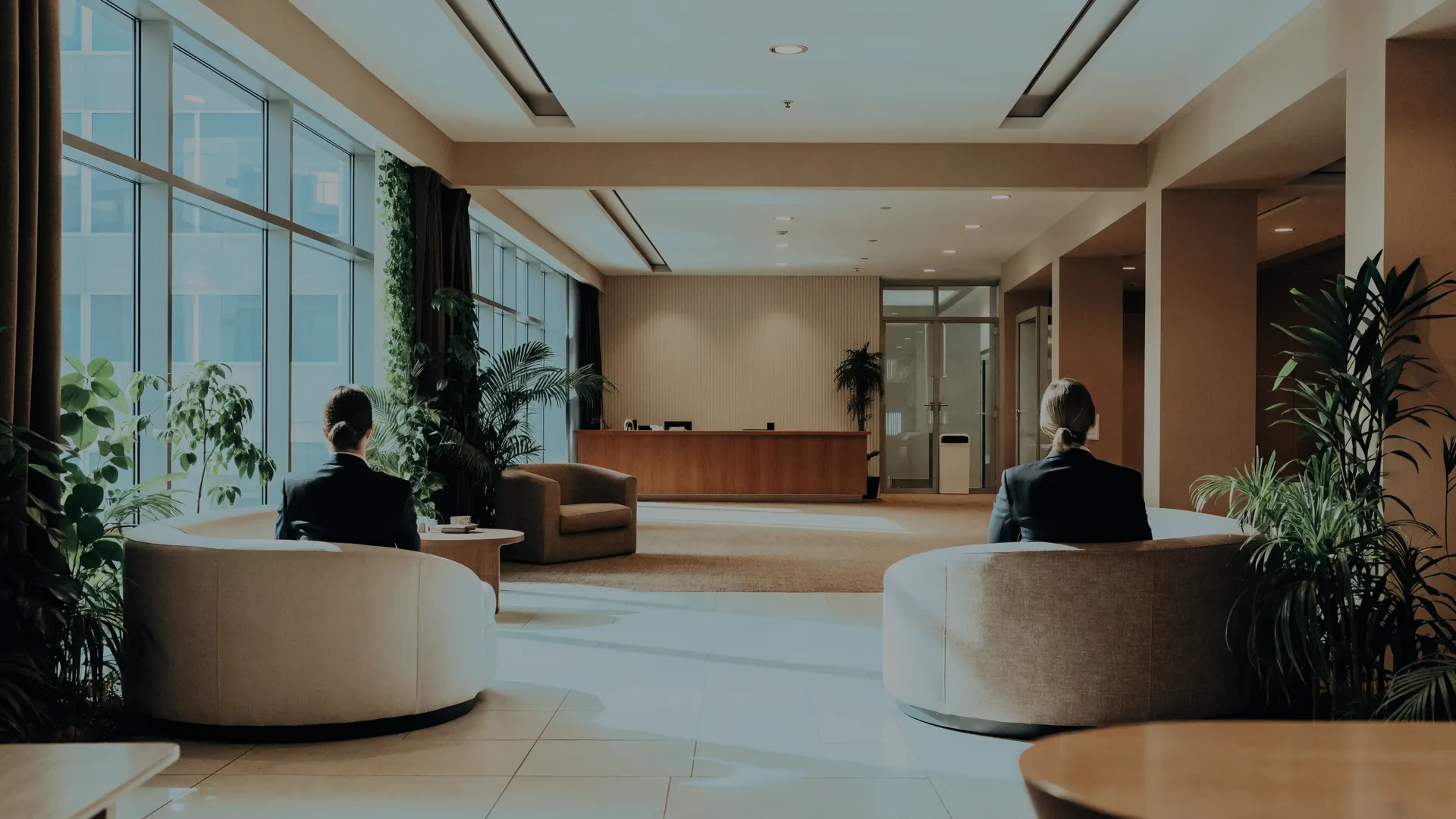 Sala de espera de una oficina, con dos personas sentadas de espaldas