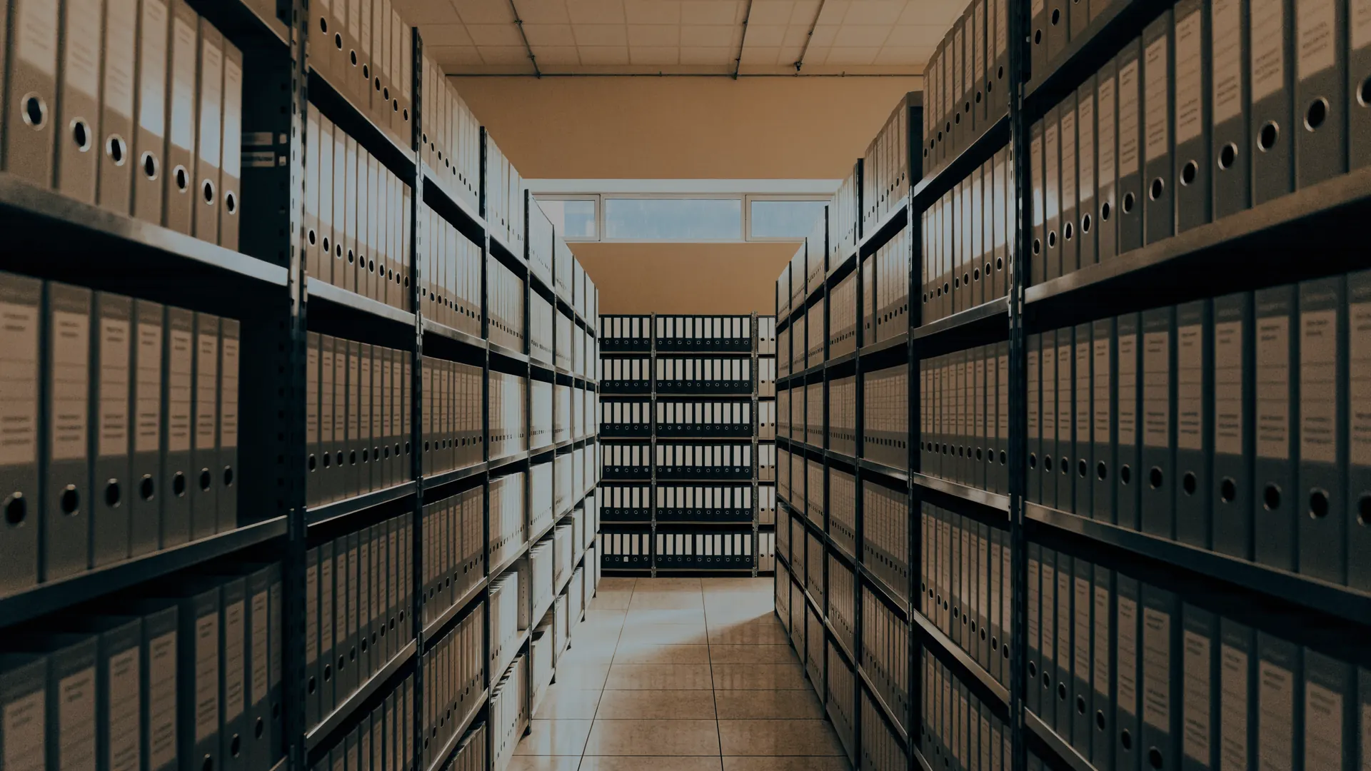 Pasillo de un archivo corporativo con estantes de carpetas hasta el fondo