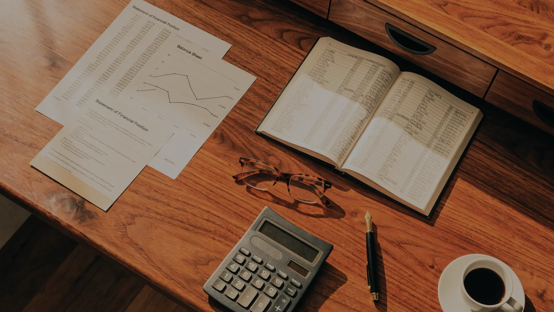Vista cenital de estados financieros, un libro contable y una calculadora
